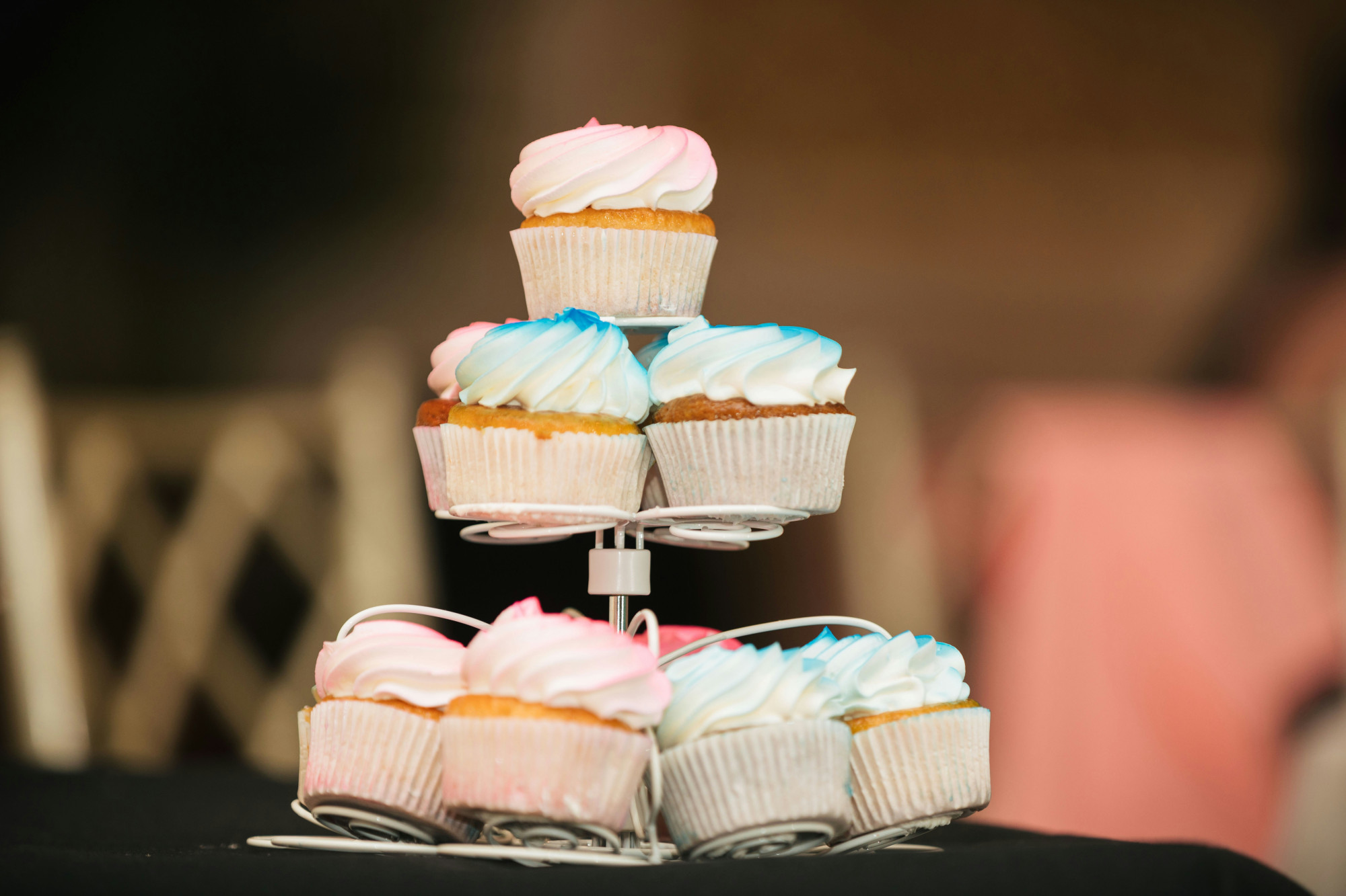 Image of a cake stand with cupcakes decorated with pink or blue icing.